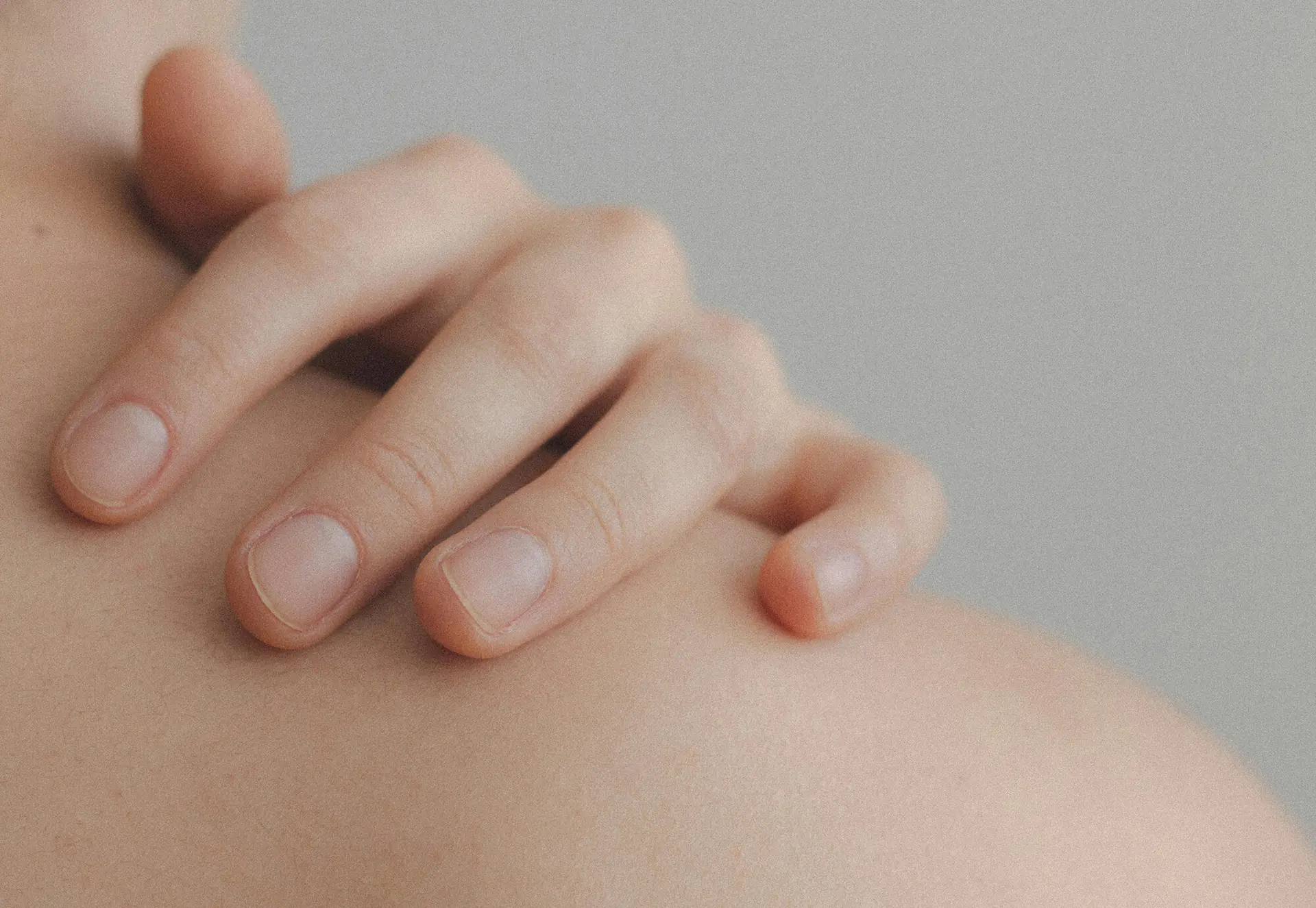 A hand resting gently on a bare shoulder, the close-up photo behind Natalia Mejia's free scar-care guide in New York